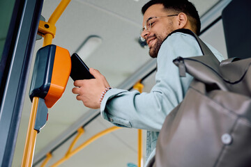 Below view of man using app on mobile phone while entering in public transport.