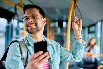 Happy man using mobile phone while riding in bus.