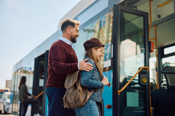 Happy father and daughter getting into city bus.