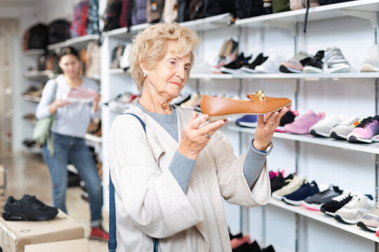 Granny choosing new shoes while standing in salesroom of shoeshop. High quality photo