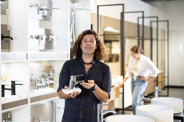 Confident man picking out new bathroom faucet in store