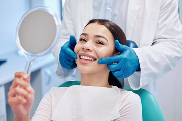 Naklejka premium The brightest smile in the room. Shot of a young woman checking her results in the dentists office.