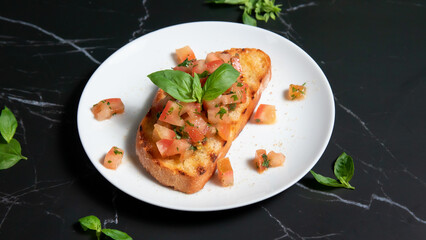 bruschetta on a white plate, with a black marble background