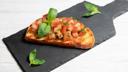 bruschetta on a black plate, on a white wooden background