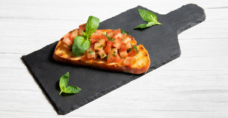 bruschetta on a black plate, on a white wooden background