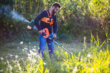 man trimming weed with weed trimmer in summer