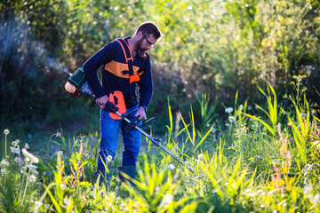 man trimming weed with weed trimmer in summer
