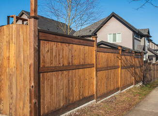 Fototapeta na wymiar Nice new wooden fence around house. Wooden brown fence with lawn. Street photo