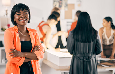United by passion. Shot of a young woman standing with her arms crossed while her coworkers collaborate in the background.