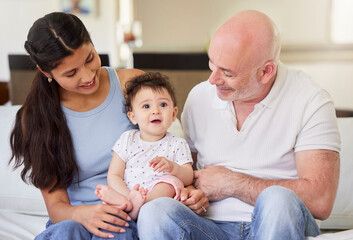 Young happy interracial couple bonding with their adopted baby at home. Little baby girl smiling...