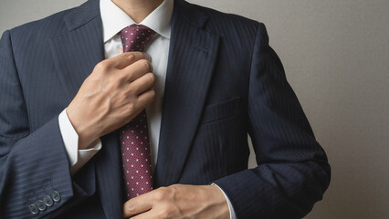 ネクタイを締めて身だしなみを整えるビジネスマン