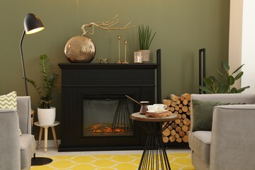 Beautiful fireplace, armchairs, table and different decor in living room. Interior design