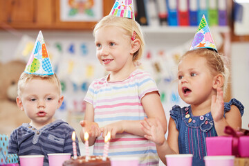 Parties make children feel extra special. Shot of a preschool children celebrating a birthday in class.
