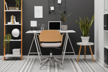 Cozy workplace with modern laptop on desk and comfortable chair at home