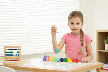 Little girl playing with Educational game Fishing for Numbers at desk in room. Learning mathematics...