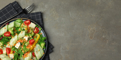 Delicious salad with lentils, cheese and vegetables served on grey table, top view. Banner design with space for text