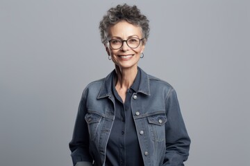Fototapeta premium Portrait of smiling senior woman in eyeglasses standing against grey background