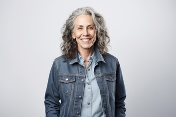 Full-length portrait photography of a grinning woman in her 50s wearing a denim jacket against a white background. Generative AI