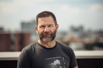 Fototapeta premium Portrait of a bearded man in a t-shirt on the roof