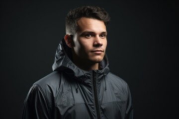 Fototapeta premium Portrait of a young man in a raincoat on a dark background