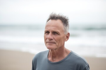 Portrait of senior man standing on beach with ocean in the background