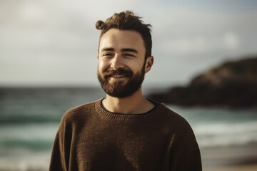 Portrait of a handsome young man standing on the beach and smiling