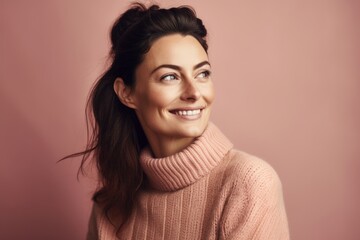 Fototapeta premium Portrait of a smiling young woman in pink sweater looking away over pink background