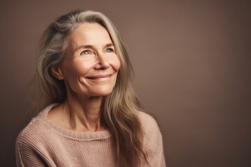 Portrait of a smiling senior woman on a brown background. Copy space.