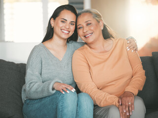 Being part of a family means smiling for photos. Shot of a mother and daughter sitting on the sofa...