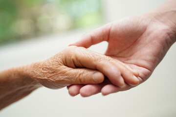 Asian young boy holding old grandmother woman hand together with love and care.