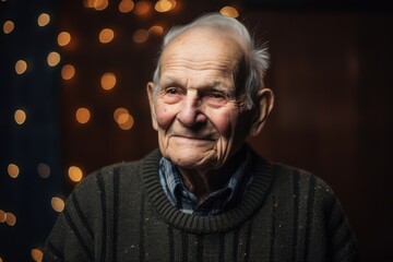 Obraz premium Portrait of a smiling senior man on christmas lights background.