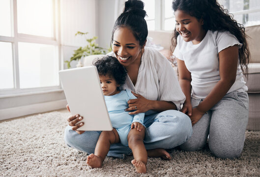 She can sit and watch these shows for hours. Full length shot of a young woman sitting in the living room with her children and using a digital tablet.