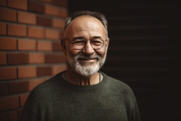 Obraz premium Portrait of a senior man with eyeglasses against brick wall
