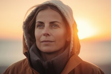 Portrait of a woman in a warm coat on the beach at sunset