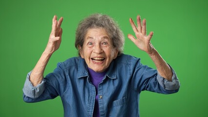Portrait of excited winner smiling elderly senior old woman with wrinkled skin and grey hair on green screen background.
