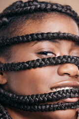 I love being wrapped in my braids. Cropped portrait of an attractive young woman posing in studio against a brown background.