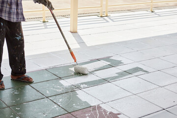 Worker holding  paint roller and painting footpath