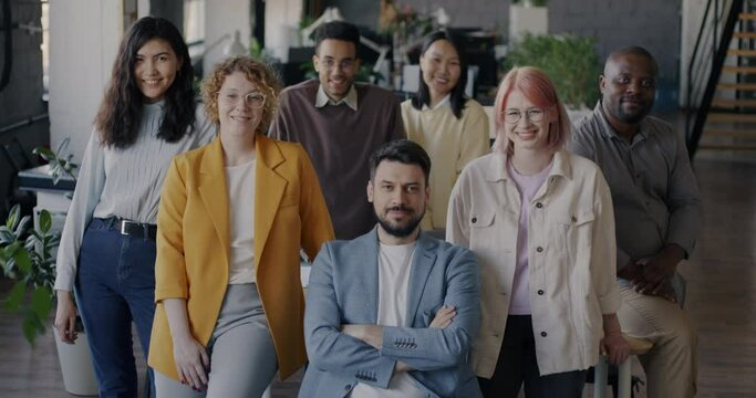Portrait of businesspeople men and women smiling in modern office standing together looking at camera. Teamwork and successful people concept.