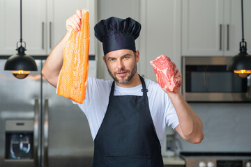 Millennial hispanic man in chef uniform hold fish and meat, salmon and beef at kitchen. Cooking...