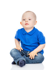 Young boy with Downs syndrom wearing casual clothes  sits and looks at camera. Isolated on white background