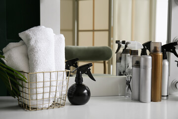 Different hair sprays and towels on table in beauty salon