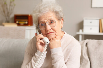 Senior woman talking by telephone at home, closeup