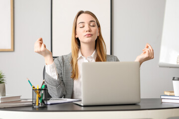 Young businesswoman meditating at table in office. Balance concept
