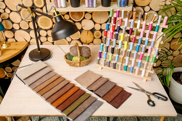 Stand with thread spools and fabric samples on table in atelier