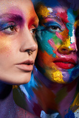 Obraz premium Life isnt all black and white. Studio shot of two young women posing with multi-coloured paint on her face.