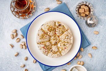 Plate with tasty Tahini halva and glass of Turkish tea on light background