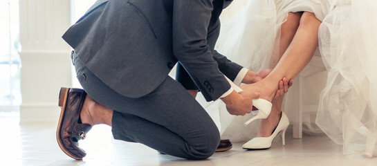 Close up of bride trying on wedding shoes with her fiance in studio. 