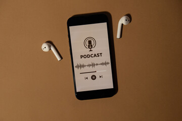 Wireless headphones and mobile phone Podcast listening website page app application on beige...