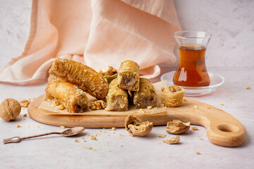 Wooden board with tasty baklava on light background