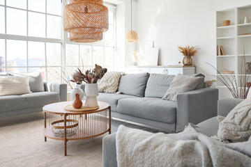 Cozy grey sofas and coffee table with bouquet of dried protea flowers in living room